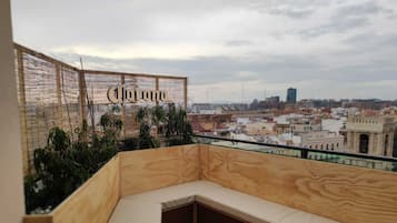 Um deck de madeira com um banco, cerca de tear e vista para a cidade.