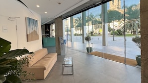 Un vestíbulo amplio con diseño moderno, que cuenta con un amplio espacio para sentarse, una mesa de centro y vistas al área exterior a través de grandes ventanales.