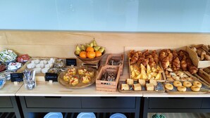 Una mesa de bufé con diversos alimentos, como frutas, pasteles y postres.