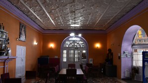 A restaurant with a high ceiling, ornate ceiling design, and a central archway. - Prince Hotel (Dehradun)