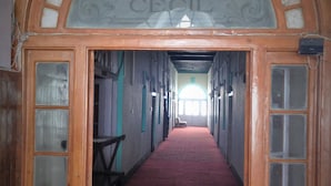 A hotel corridor with a red carpet, wooden doors with glass panels, and a sign above the entrance that reads "HOTEL CEIL". - Prince Hotel (Dehradun)
