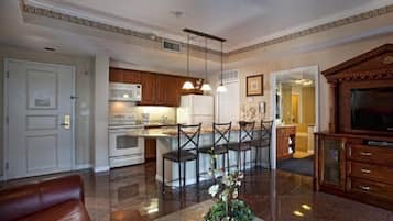 Una cocina moderna con electrodomésticos blancos, un comedor con mesa de vidrio y una sala de estar con sofá de cuero.