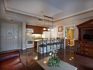 A modern kitchen with white appliances, a dining area with a glass table, and a living room with a leather couch. - Westgate Palace (Orlando)