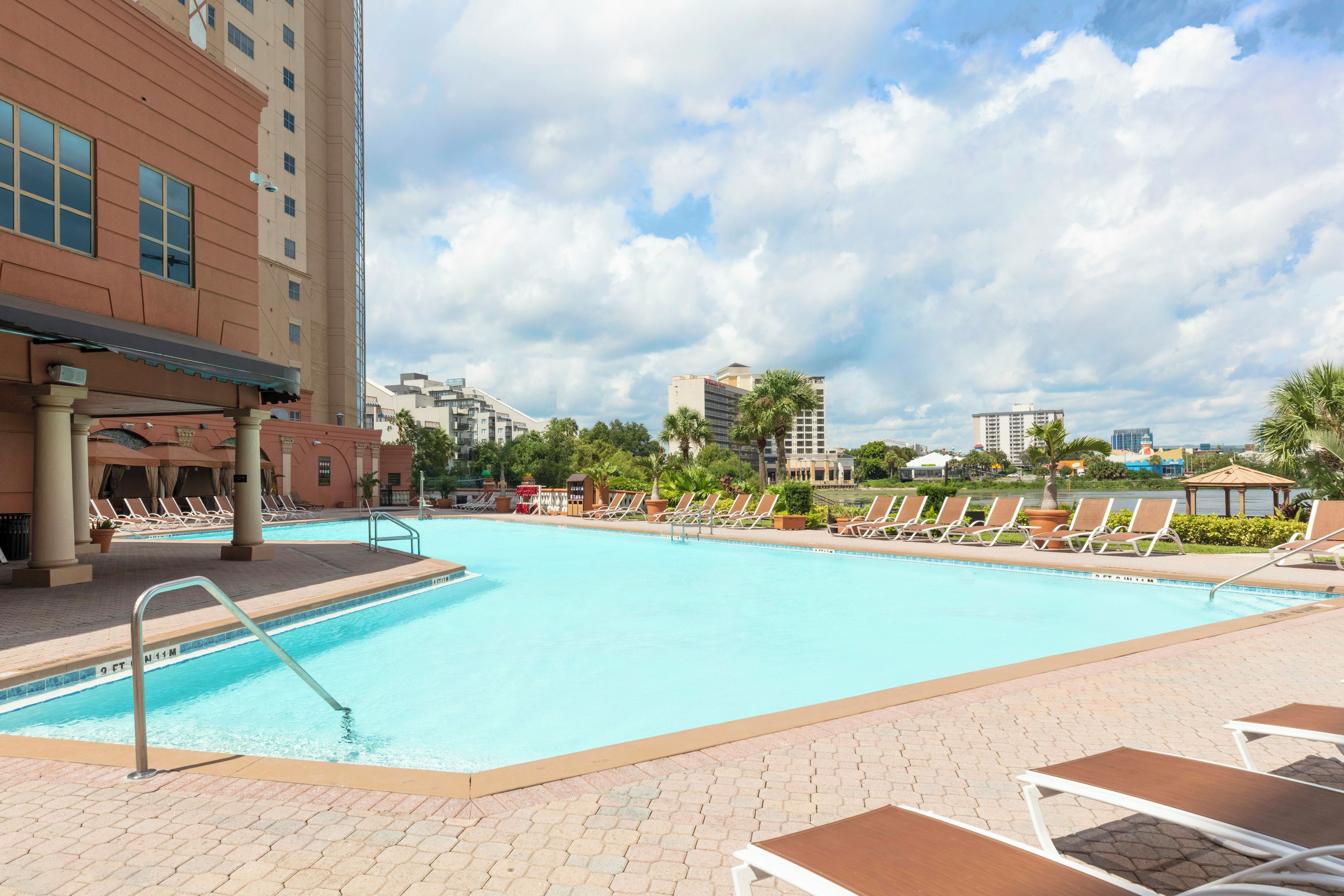 A swimming pool with lounge chairs and a cityscape in the background.
