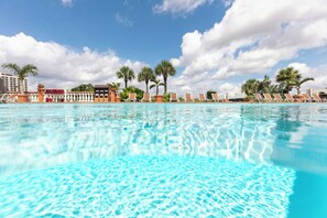 A clear swimming pool with lounge chairs and palm trees in the background. - Westgate Palace (Orlando)