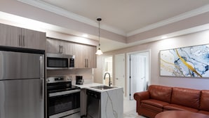 A modern kitchen with stainless steel appliances, a marble island, and a brown leather sofa. - Westgate Palace (Orlando)
