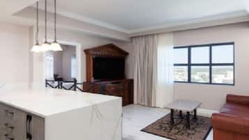 Sala de estar moderna com ilha de mármore, área de refeições, sofá de couro marrom e uma grande janela com vista para a cidade.