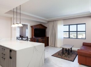 A modern living room with a marble island, a dining area, a brown leather sofa, and a large window with a city view. - Westgate Palace (Orlando)