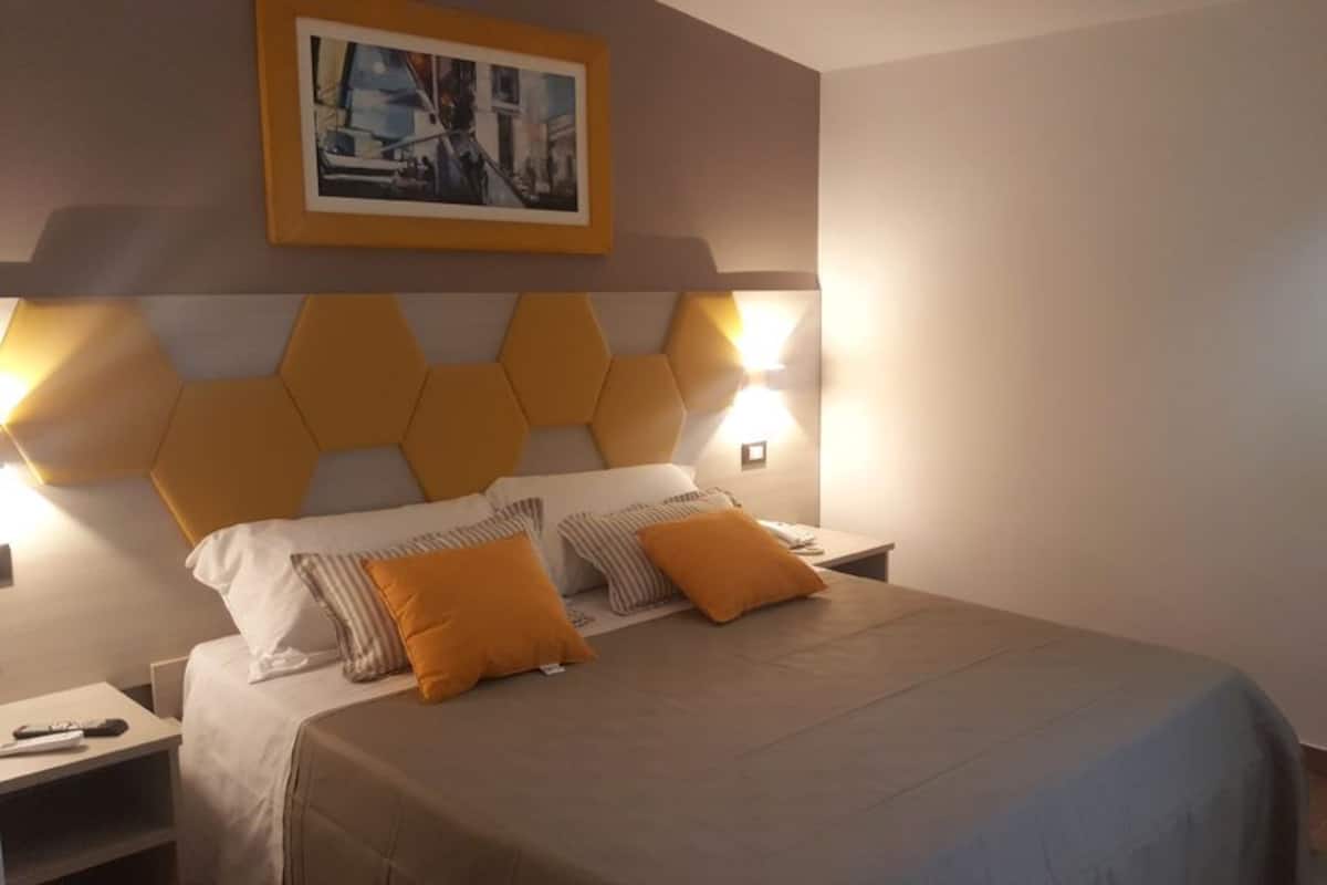 Une chambre d’hôtel avec un lit, une table de chevet et un tableau accroché au mur.