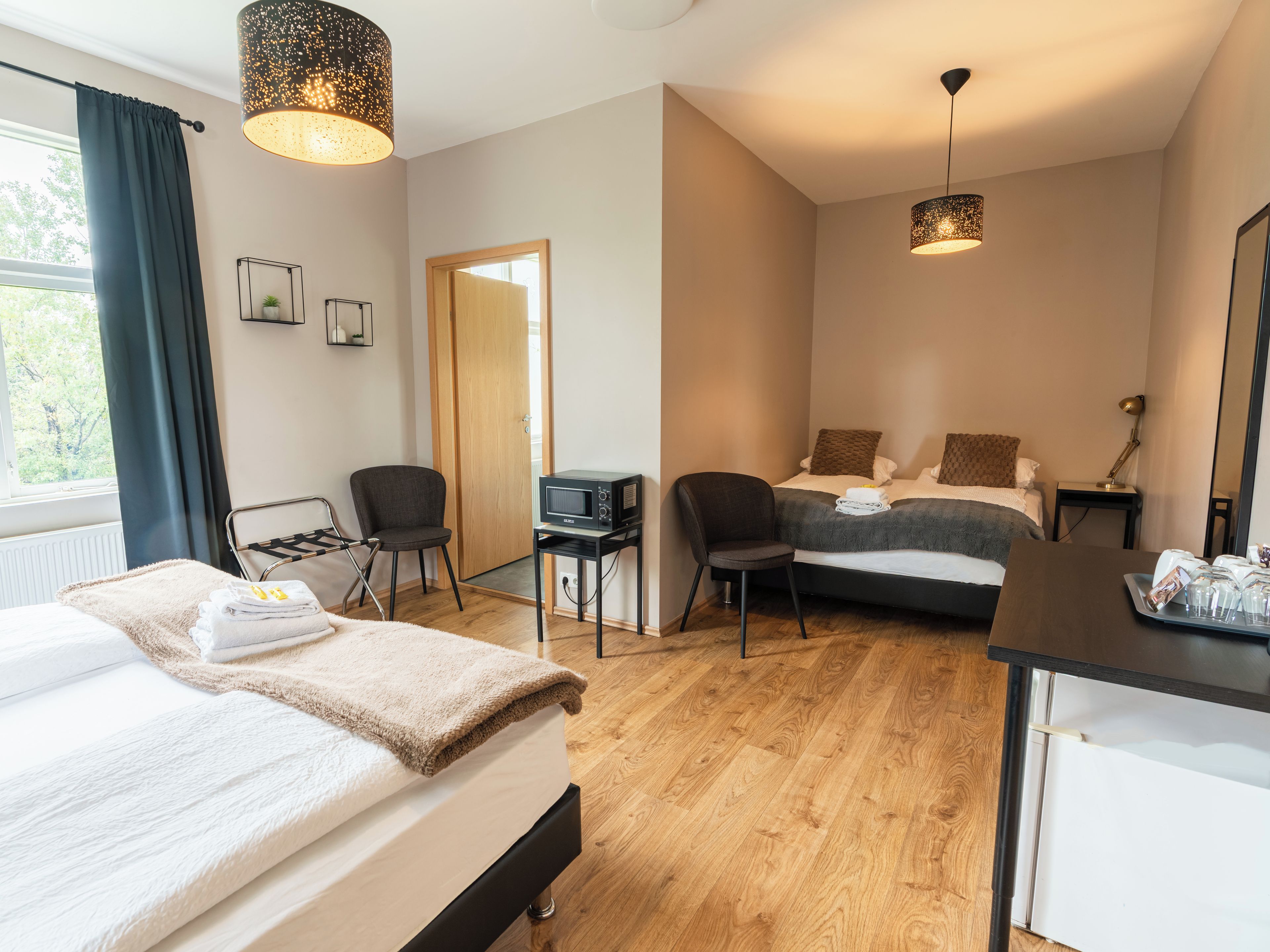 Une chambre d’hôtel avec un lit, deux chaises, un bureau, une télévision et une grande fenêtre.