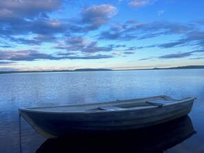 A small boat tied to a dock with calm water and a clear sky.