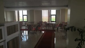 Un comedor amplio con una larga alfombra roja, varias mesas y sillas.