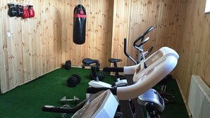 Un gimnasio con equipo de ejercicio, un saco de boxeo y una fila de guantes de boxeo en la pared.
