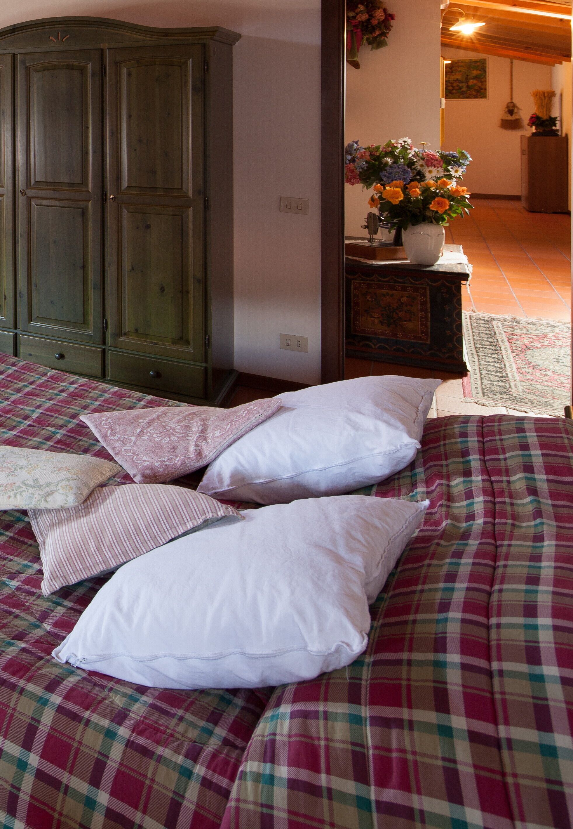 Ein Schlafzimmer mit einem Bett, Kissen, einem Schminktisch und einem Blumenstrauß.