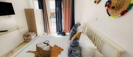 Une chambre d’hôtel équipée d’un lit, d’une télévision, d’une fenêtre avec des rideaux et d’un climatiseur fixé au mur.