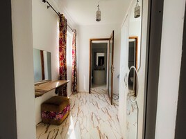 Un pasillo con suelo de mármol, un banco de madera, un espejo y una puerta que da a un baño.