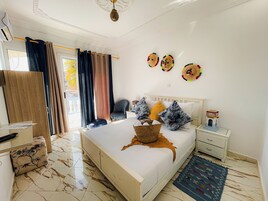 Un dormitorio con cama, mesita de noche, silla y vistas al exterior.