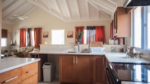 Una cocina con armarios de madera, encimera blanca, un fregadero y una estufa.