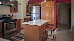 Una cocina con armarios de madera, un refrigerador de acero inoxidable y una encimera blanca.