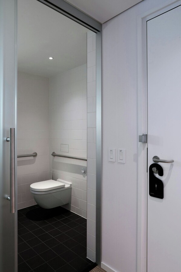 A modern bathroom with a toilet, a shower, and a door with a towel dispenser. - citizenM Seattle South Lake Union (Seattle)