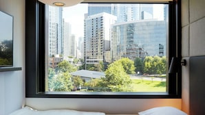 A hotel room with a large window offering a view of high-rise buildings and a park. - citizenM Seattle South Lake Union (Seattle)