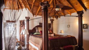 A traditional four-poster bed with a wooden canopy, a chandelier, and a ceiling fan in a room with white walls and wooden beams. - Jewel In The Sand (Runaway Bay)