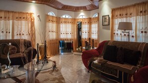 A spacious living room with two sofas, a glass coffee table, and a red armchair. There are decorative vases and a mirror on the coffee table. - Jewel In The Sand (Runaway Bay)