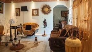 A living room with a sofa, armchair, and a glass coffee table. There is a wall clock and a framed picture on the wall. - Jewel In The Sand (Runaway Bay)