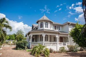 A large, two-story house with a balcony and a porch, surrounded by greenery. - Jewel In The Sand (Runaway Bay)