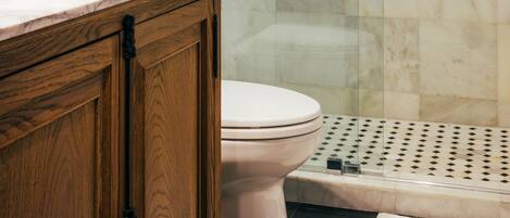 A modern bathroom with a glass-enclosed shower, a wooden vanity, and a toilet.