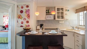 A kitchen with a central island, two bar stools, a microwave, and a sink.