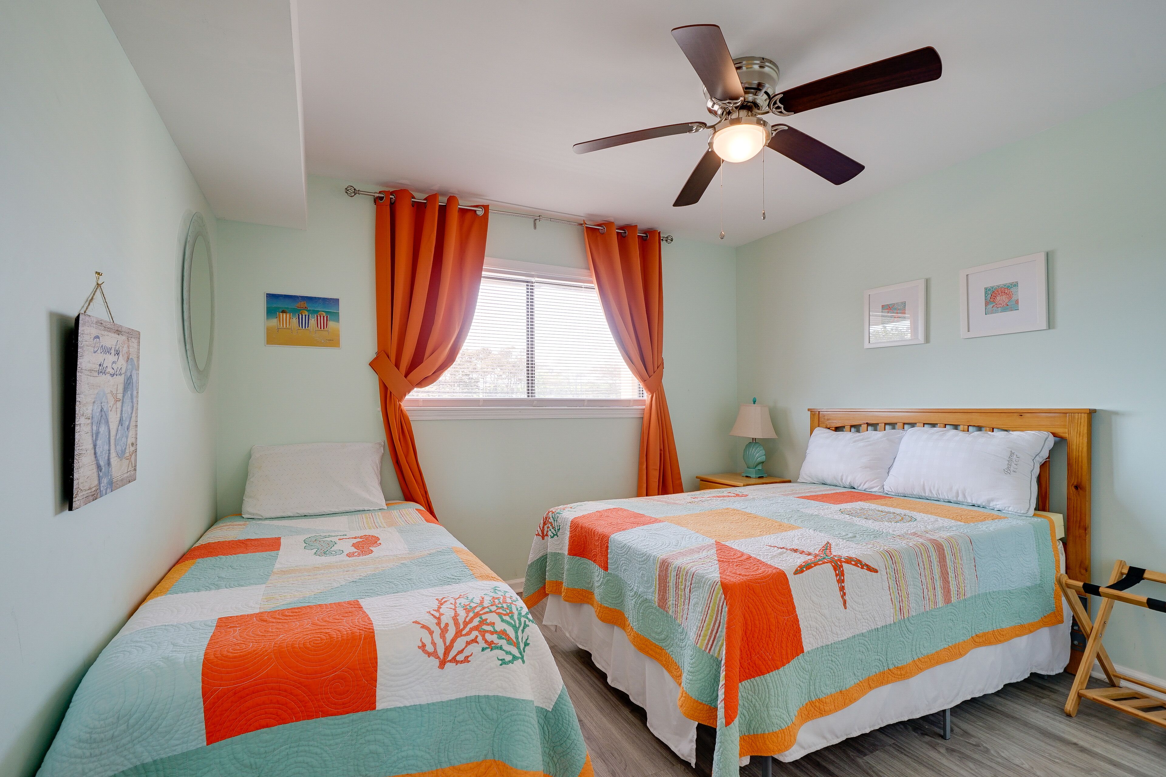 A bedroom with two beds, a ceiling fan, and a window with curtains.