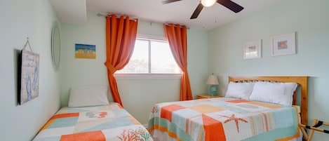 A bedroom with two beds, a ceiling fan, and a window with curtains.