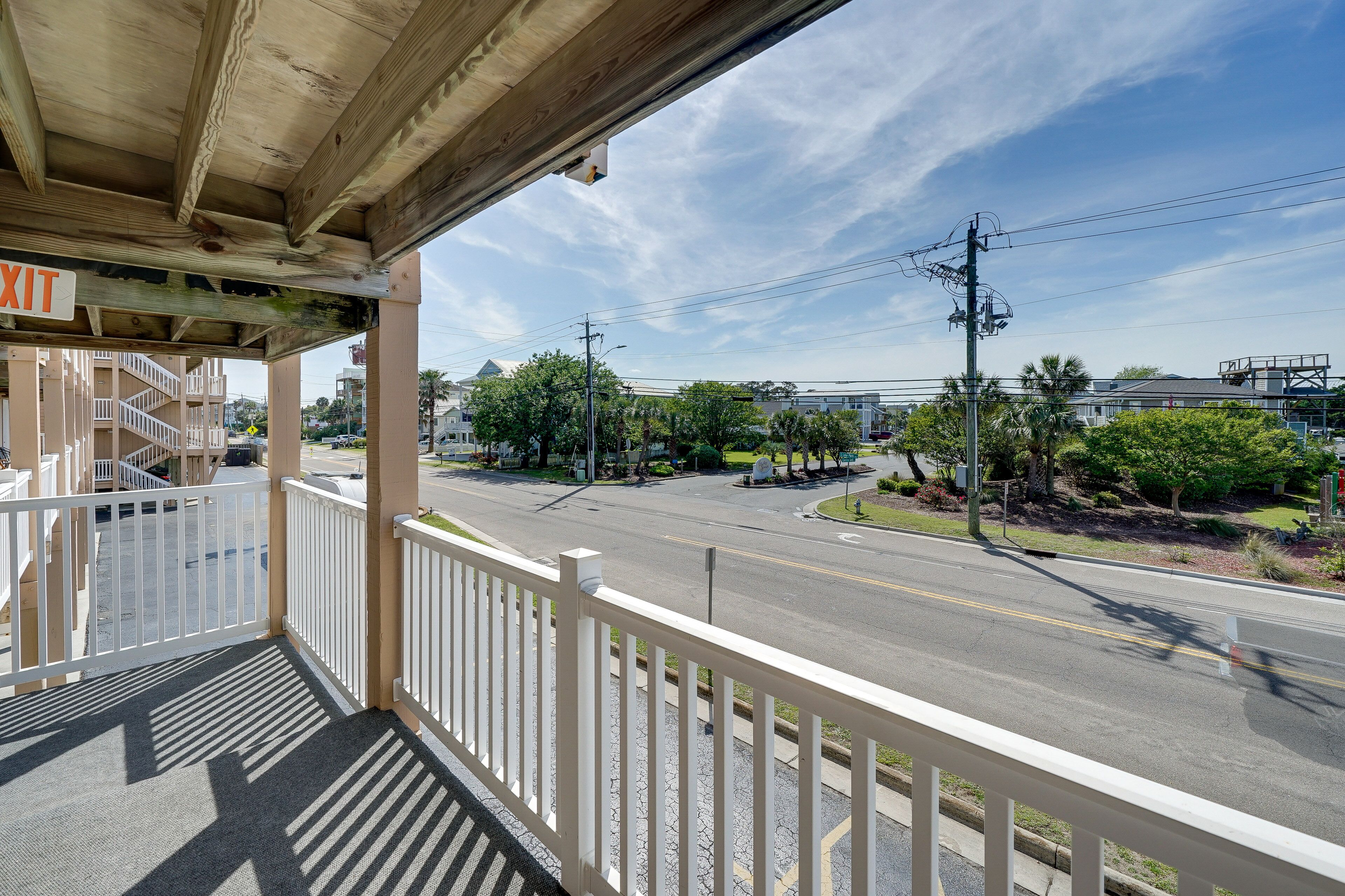 A covered balcony with a view of a street and buildings.