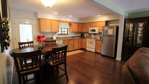 A spacious kitchen with wooden cabinets, a dining table with chairs, a refrigerator, and a microwave.
