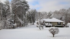 A snow-covered landscape with a house and trees.