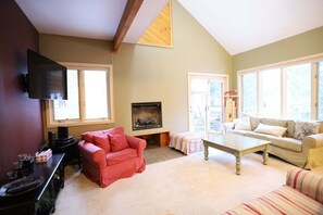 Ein Wohnzimmer mit Kamin, Wandfernseher und zwei Sofas.