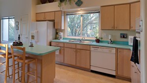 A kitchen with wooden cabinets, a central island with bar stools, a window with a view, and a sink.