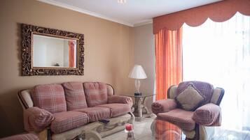 A living room with a sofa, armchair, and a glass coffee table.