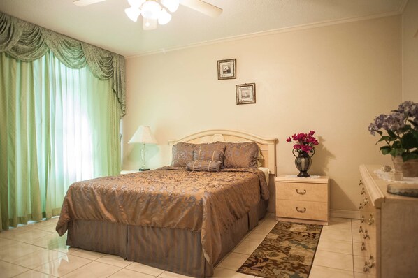 Un dormitorio ordenado con cama, mesitas de noche y cómoda.