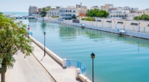 Una passeig marítim amb una vista despejada del mar, un camí per a vianants i edificis al llarg de la costa.