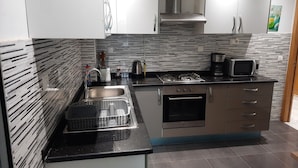 A modern kitchen with a gas stove, microwave, and stainless steel appliances. - La Perle Bleue (Le Kram)