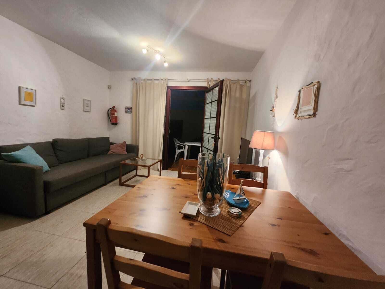 Una sala de estar con una mesa de comedor de madera, un sofá y una lámpara.