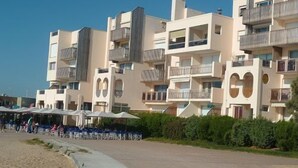 Un hotel de varios pisos con balcones, un área de estar al aire libre cubierta y un sendero pavimentado.