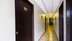 Corredor de hotel com portas de madeira, uma placa numérica em uma porta e piso de azulejos.