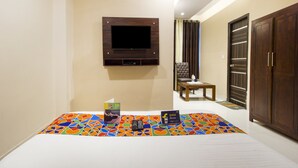 Quarto de hotel com cama, televisão presa na parede, uma mesinha e um guarda-roupa.