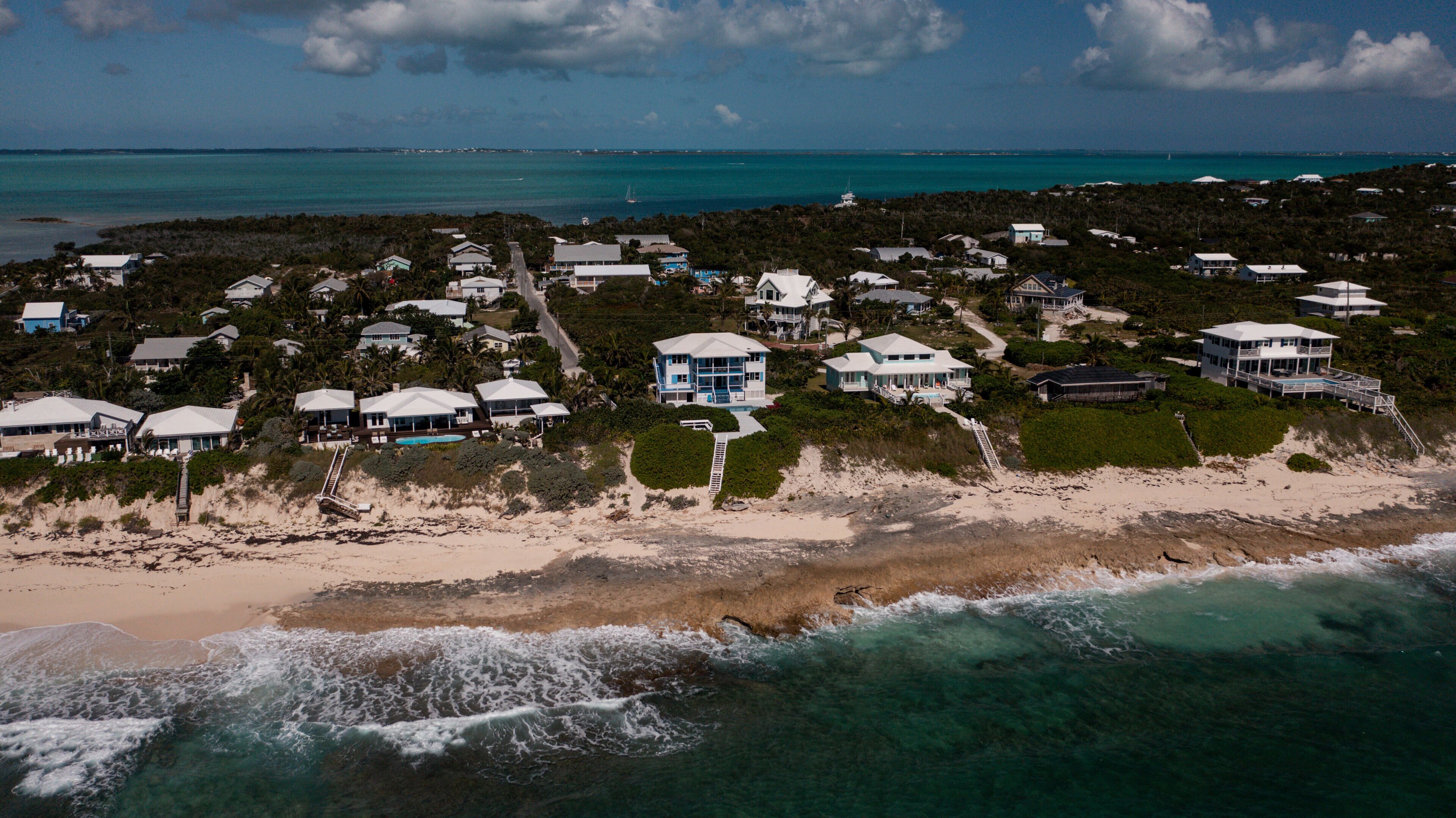 An aerial view of a coastal residential area with houses, a beach, and the ocean.