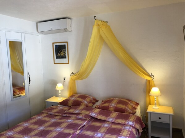 A bedroom with a bed, two bedside tables with lamps, a wardrobe, a wall-mounted air conditioner, and a framed picture. - Air-conditioned quiet vacation home with private pool 2 mn. from the village (Le Plan-De-La-Tour)