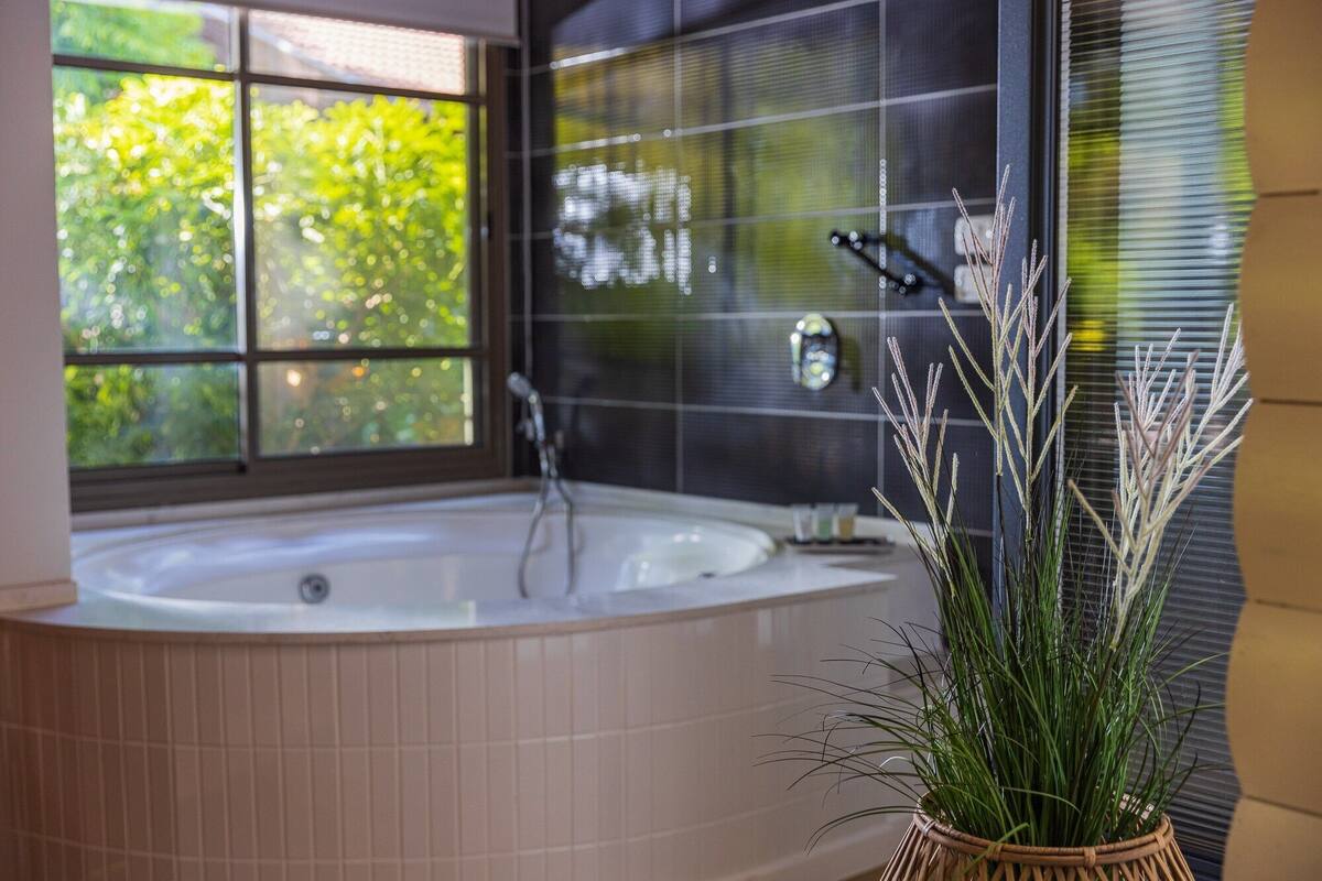 Een moderne badkamer met een vrijstaand bad, een groot raam en een plant in pot.