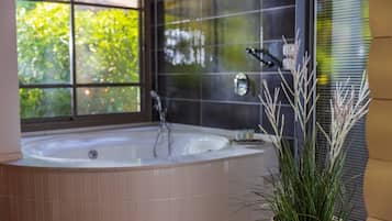 A modern bathroom with a freestanding bathtub, a large window, and a potted plant.